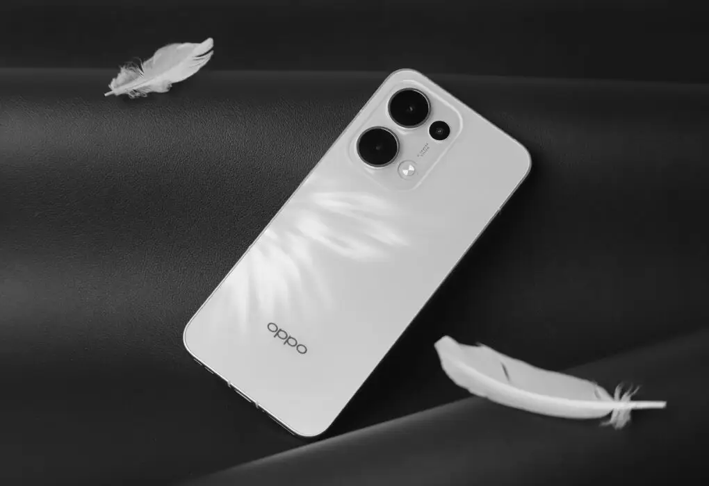 Minimalist white smartphone with feathers on a black surface, creating a modern and sleek aesthetic.