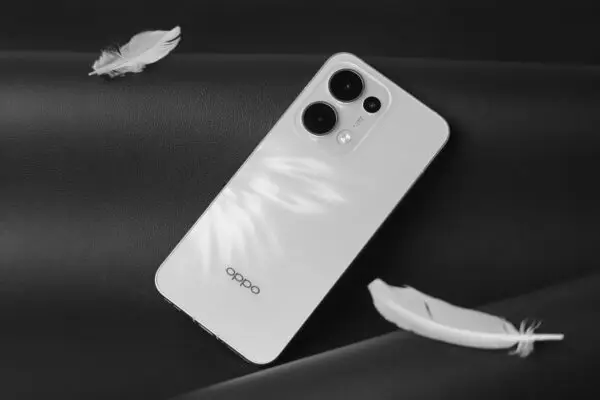 Minimalist white smartphone with feathers on a black surface, creating a modern and sleek aesthetic.