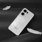 Minimalist white smartphone with feathers on a black surface, creating a modern and sleek aesthetic.